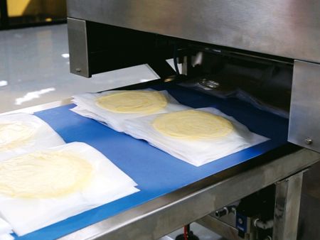 ANKO’s PP-2 Automatic Filming and Pressing Machine places a piece of film and presses the dough flat